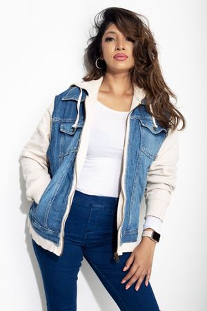 A casual denim outfit with a white and blue jean jacket paired with dark denim overalls against a white backdrop.