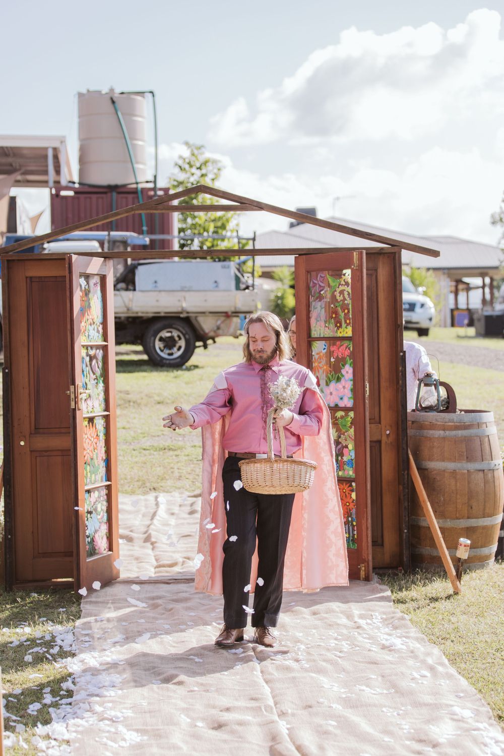 Wedding guests walk through rustic wooden doors decorated with flowers.