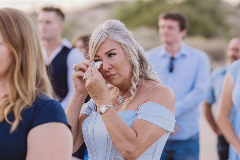 Wedding guests in blue and formal attire gather during an outdoor reception.