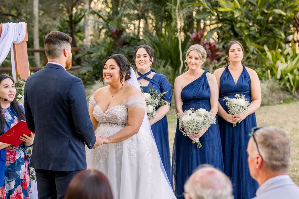 Wedding party members in navy dresses and suits gathered for outdoor ceremony photos.
