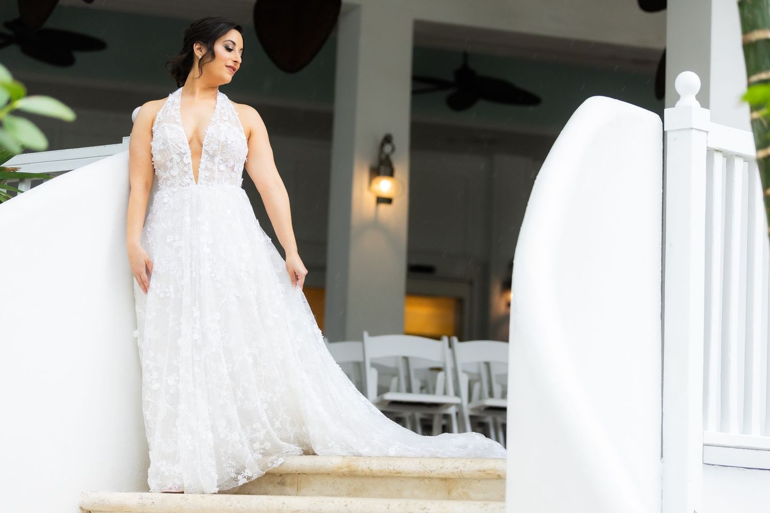 Full-length view of wedding dress with detailed lace overlay on sunny tropical porch.