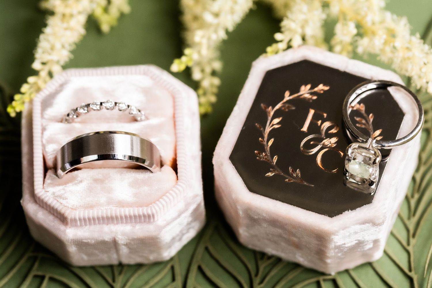 Close-up of elegant wedding rings styled on geometric marble holders with delicate floral accents.