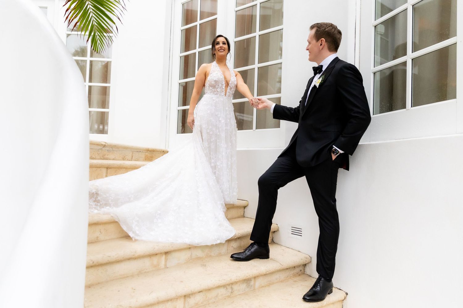 Modern white wedding venue with tropical palm accents and elegant windows.