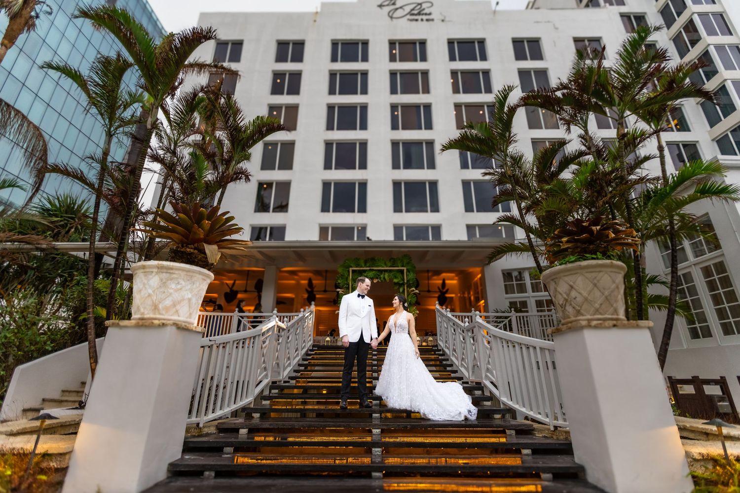 Wedding couple descending outdoor stairs at a modern beachfront venue.