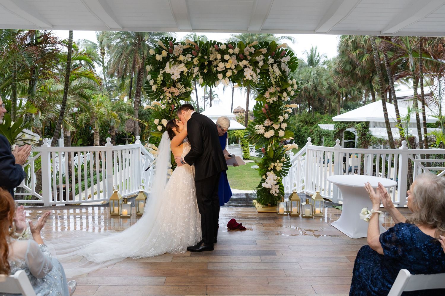 Outdoor wedding ceremony setup with white gazebo and tropical garden backdrop.