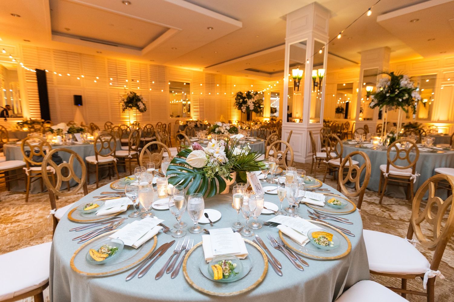 Panoramic view of wedding reception tables set with formal place settings and decorative centerpieces.