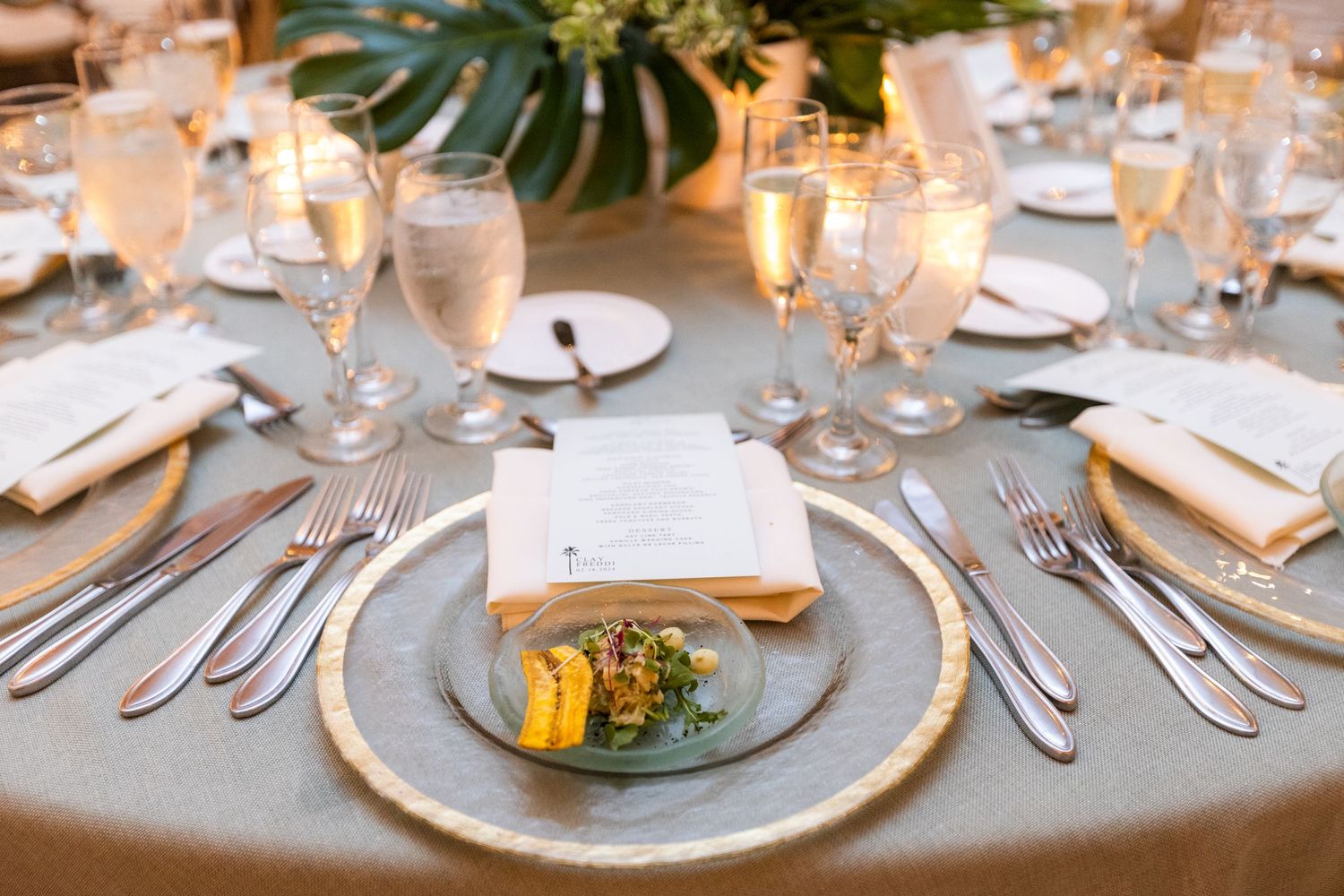 Close-up of formal place settings with multiple utensils and elegant glassware at wedding reception.