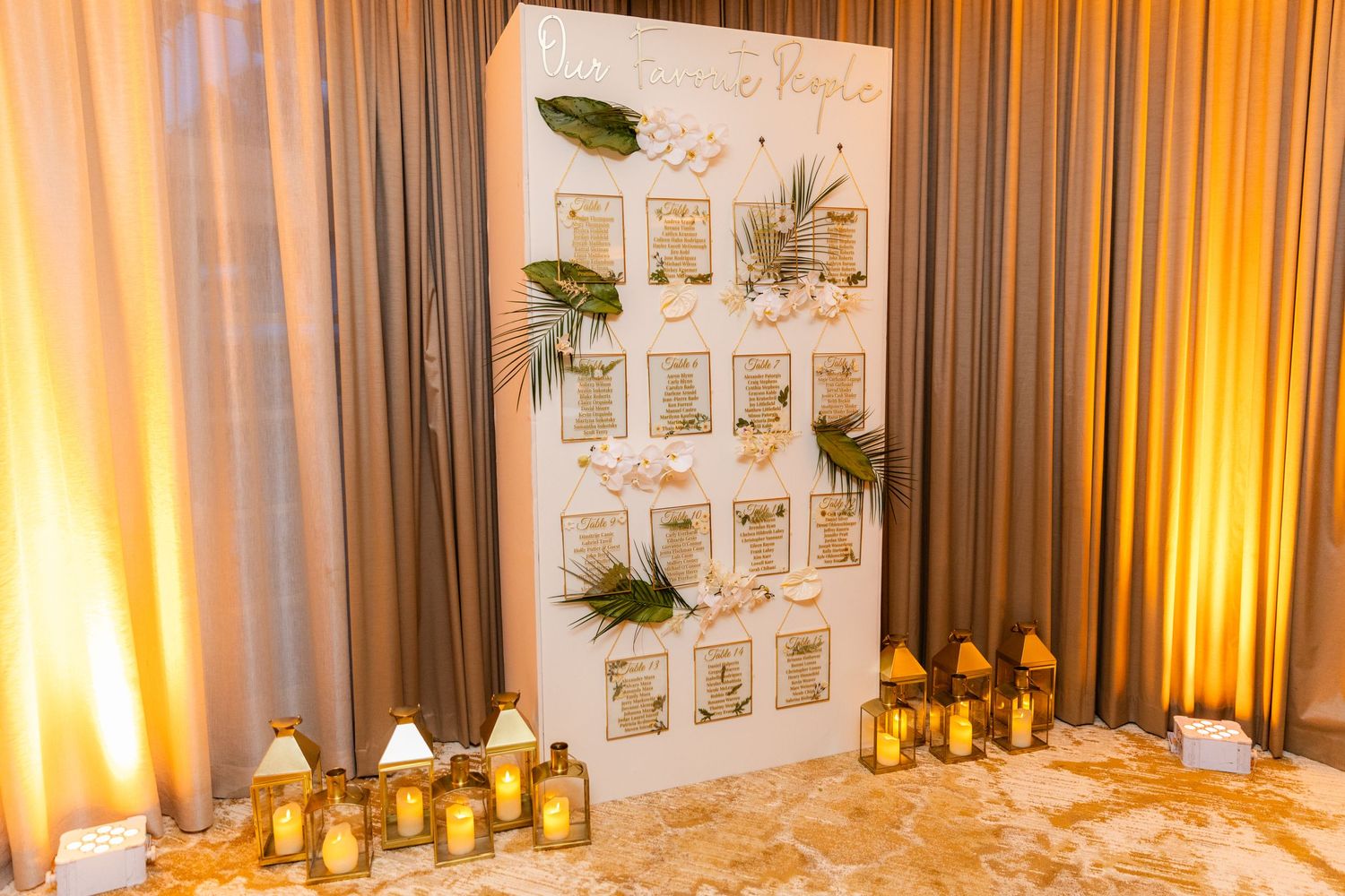 Elegant wedding reception venue decorated with white curtains and warm uplighting creates a romantic atmosphere.