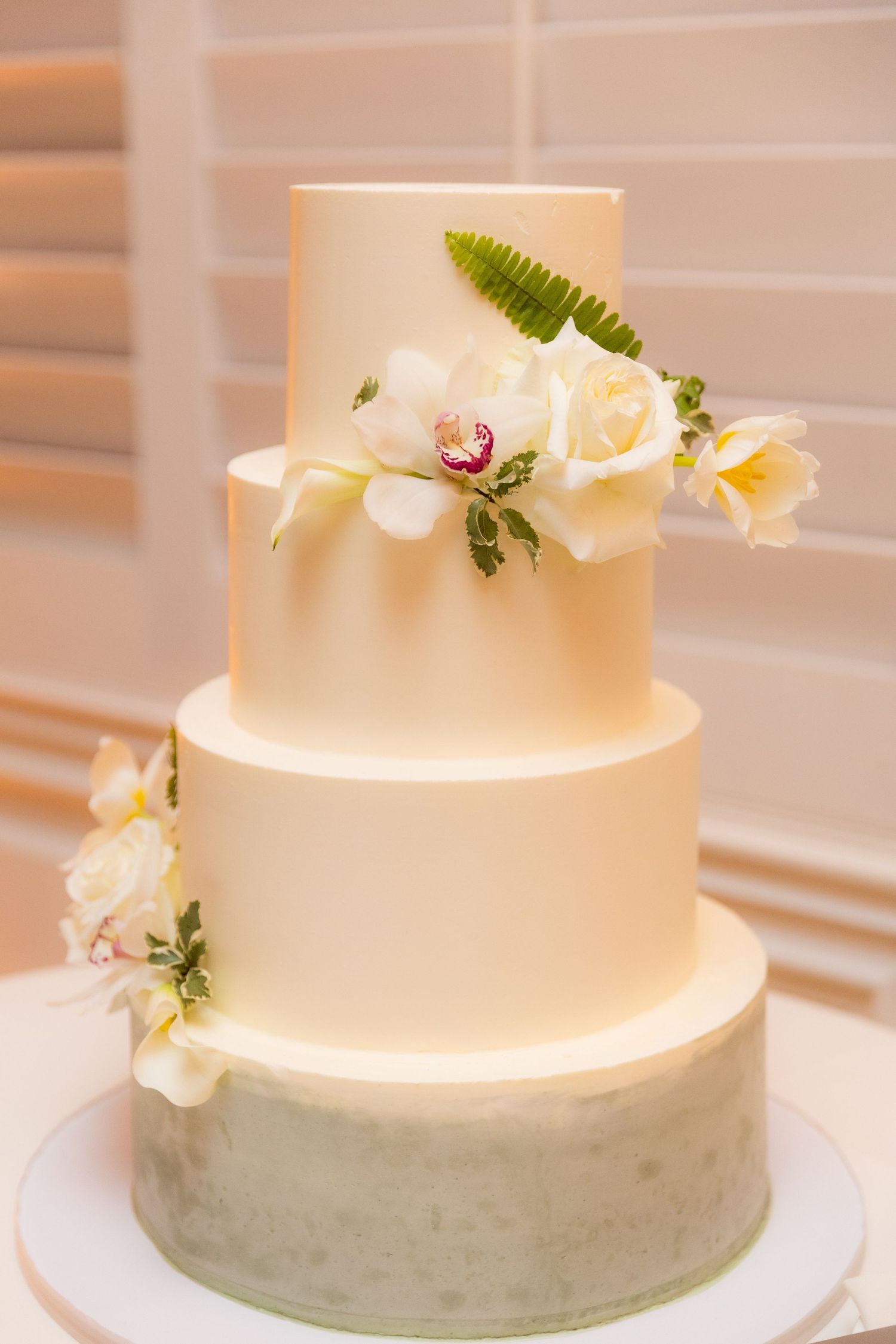 Two-tiered white wedding cake with fresh floral decorations in a minimalist design.