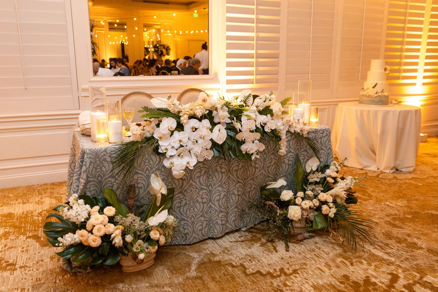 Wedding reception table decorated with lush floral arrangements and warm ambient lighting.