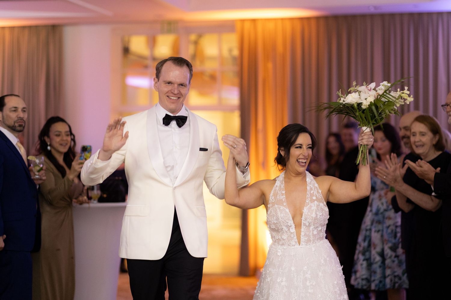 Wedding celebration in progress with guests dancing on the reception floor under warm lighting.