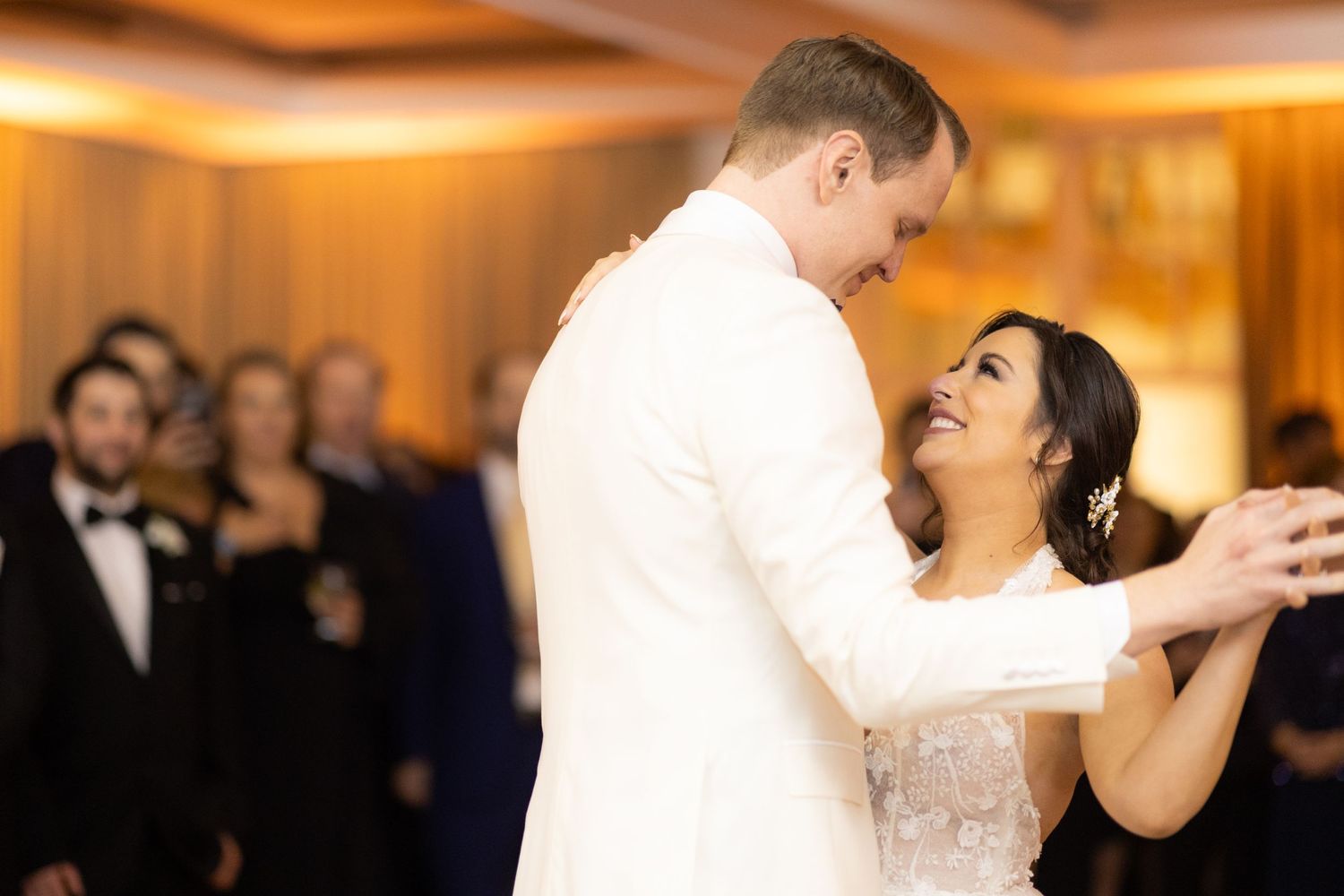 Couple performing romantic dip during wedding dance on reception floor with warm lighting.