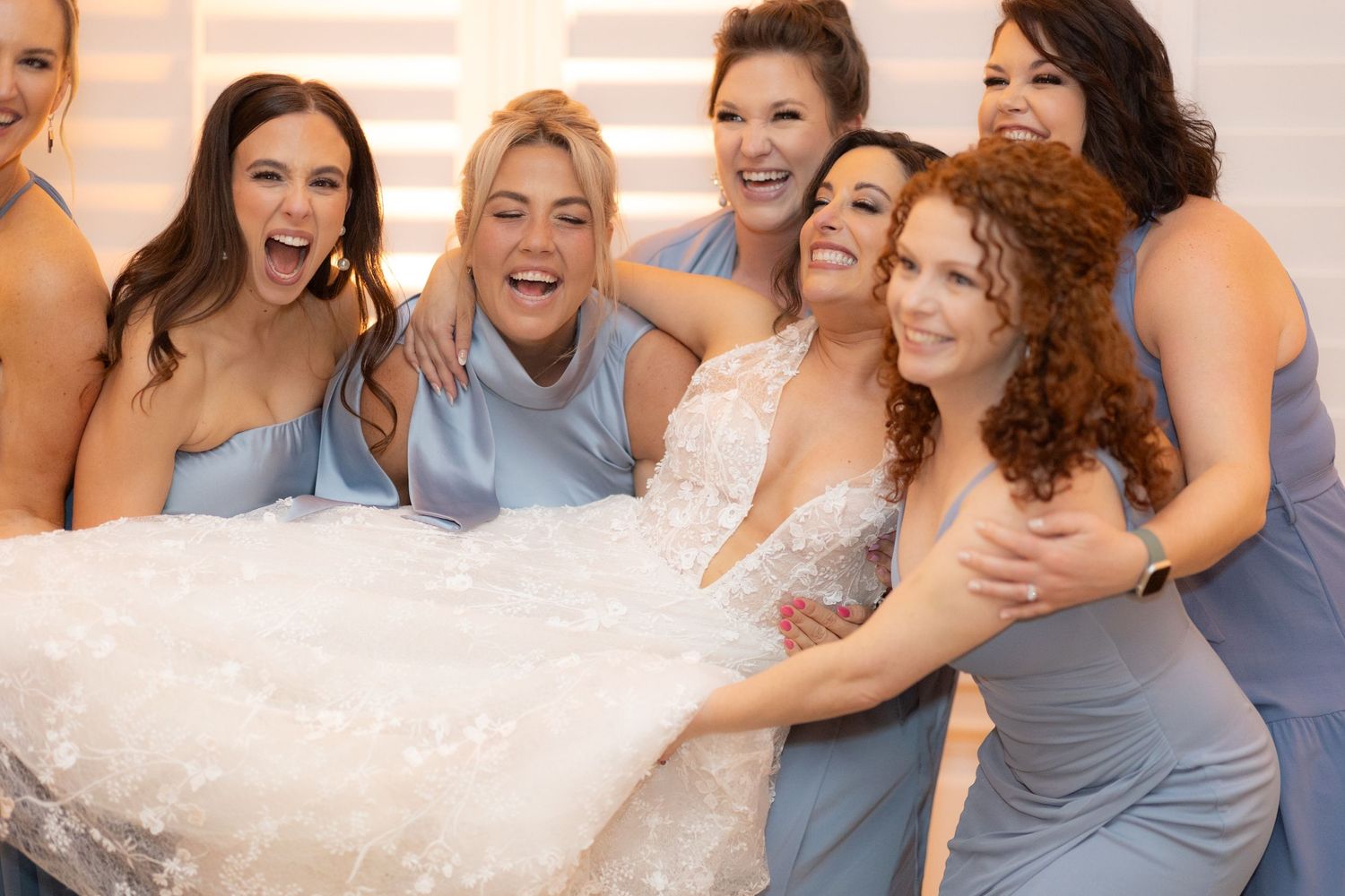 Wedding party in light blue dresses poses together for fun group photos.