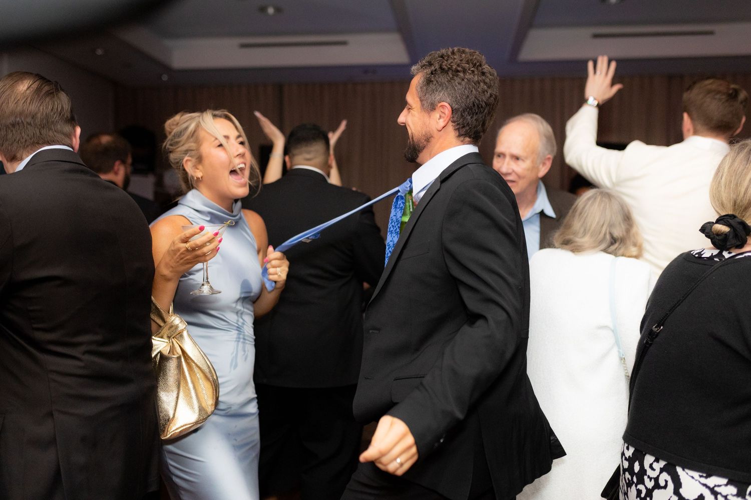 Wedding guests dance and celebrate on the reception dance floor.