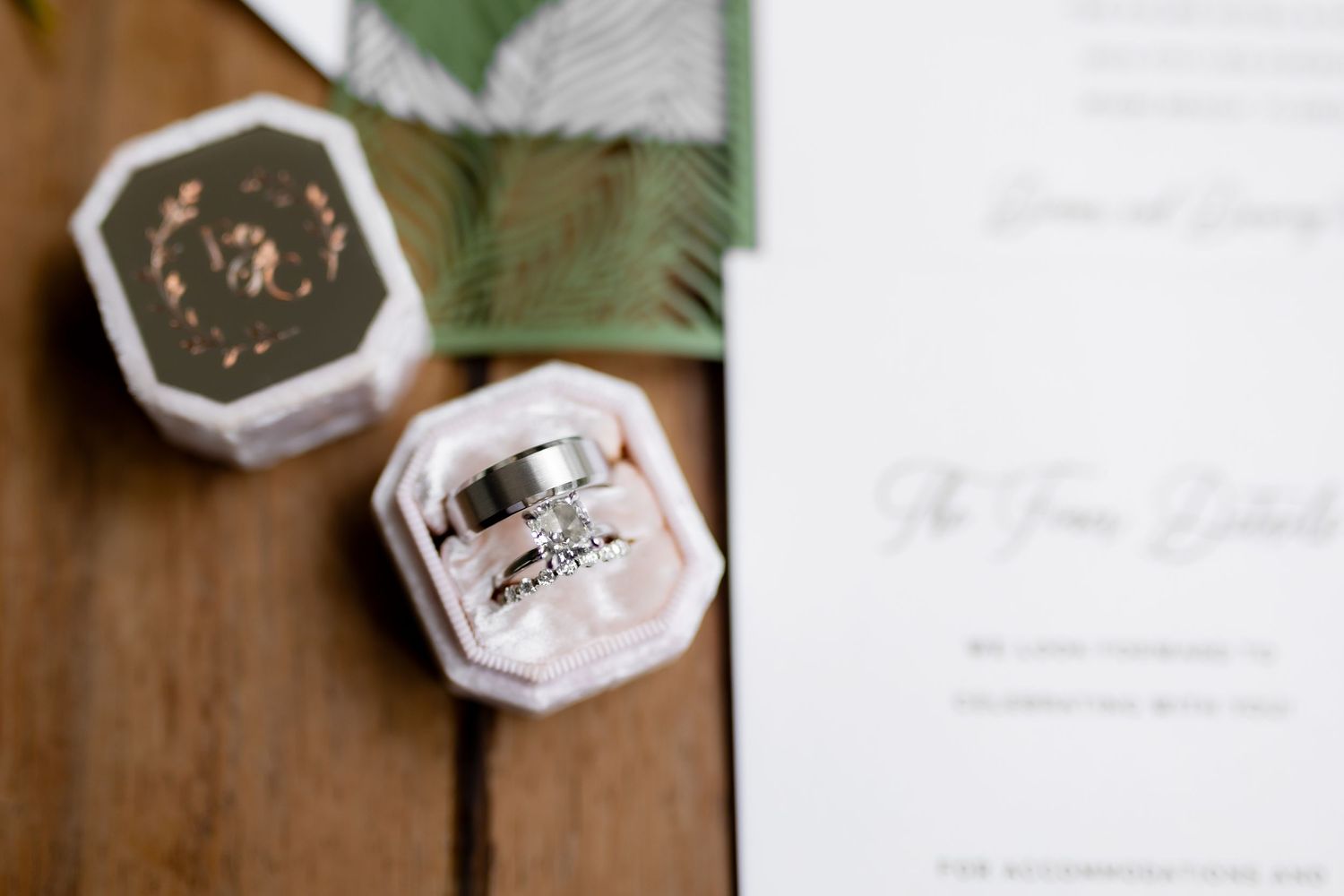 Wedding stationery and invitations arranged with floral elements and palm leaves on a rustic wooden background.