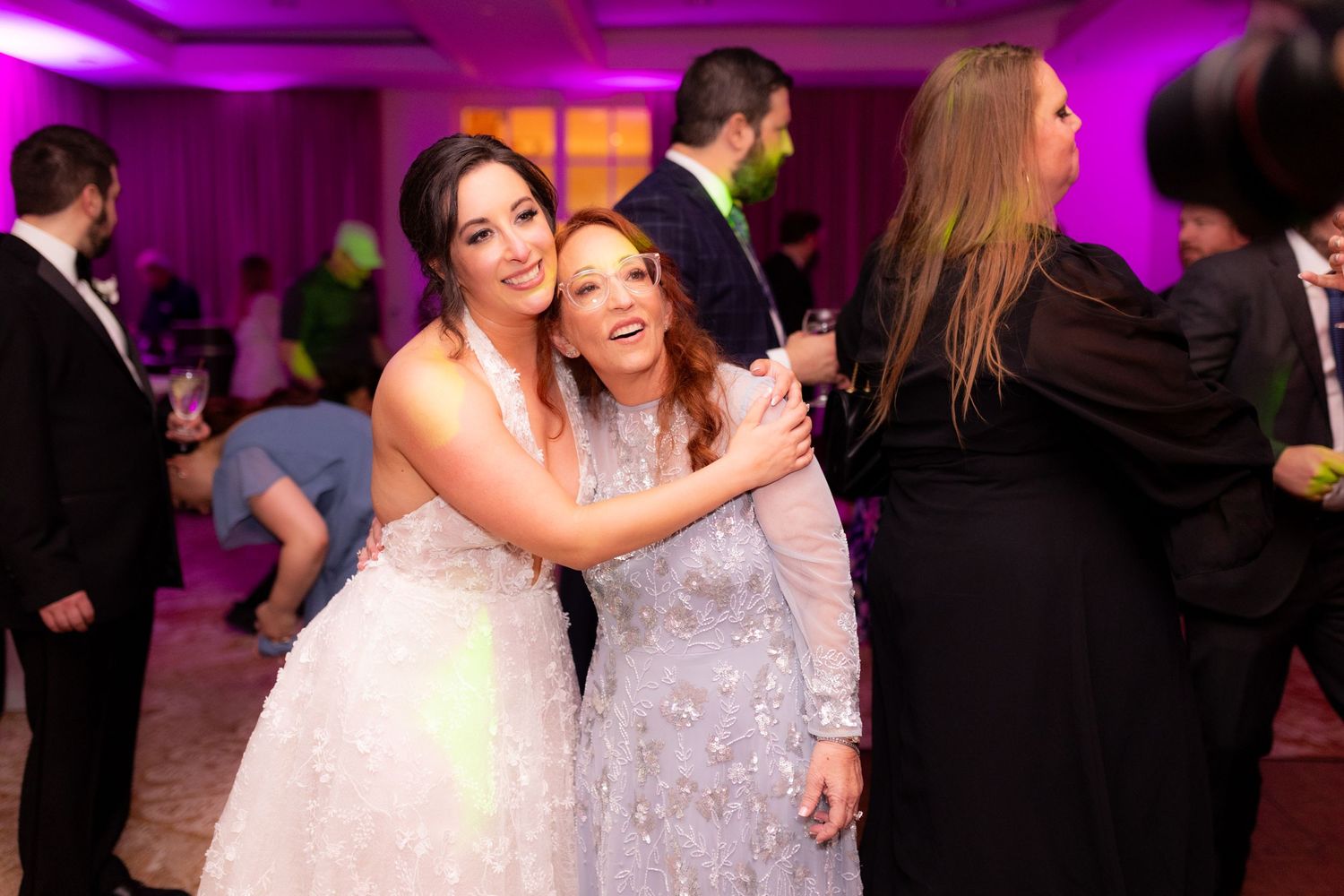 Wedding reception dance floor lit with purple lighting as guests celebrate.