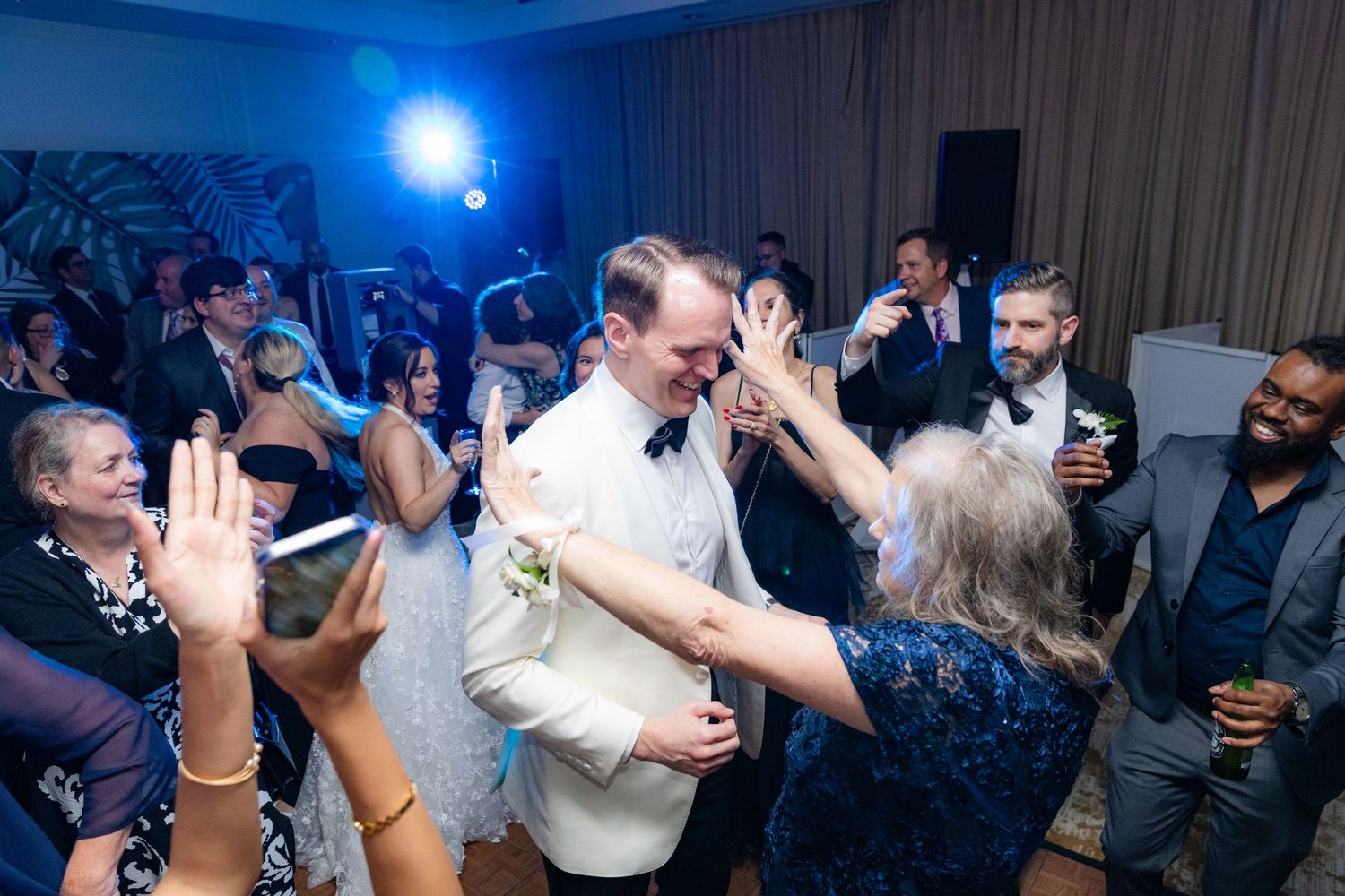 Wedding reception dance floor illuminated with blue lights as guests party.