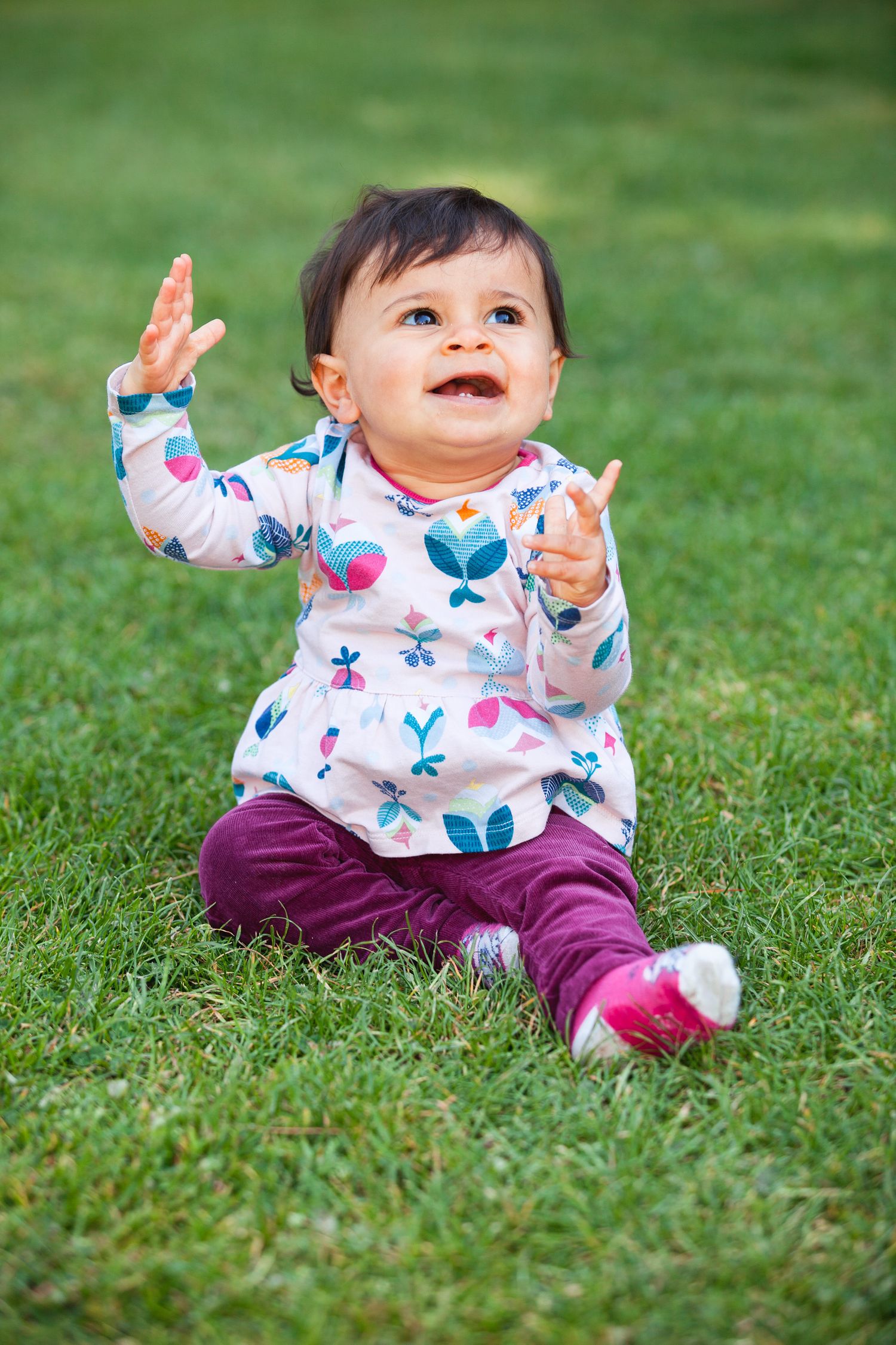Un bébé assis dans l'herbe avec une mimique joyeuse