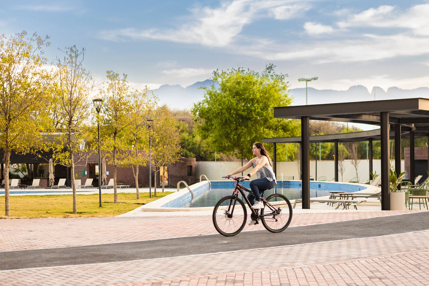 Person riding bicycle past modern bus shelter on sunny urban street.