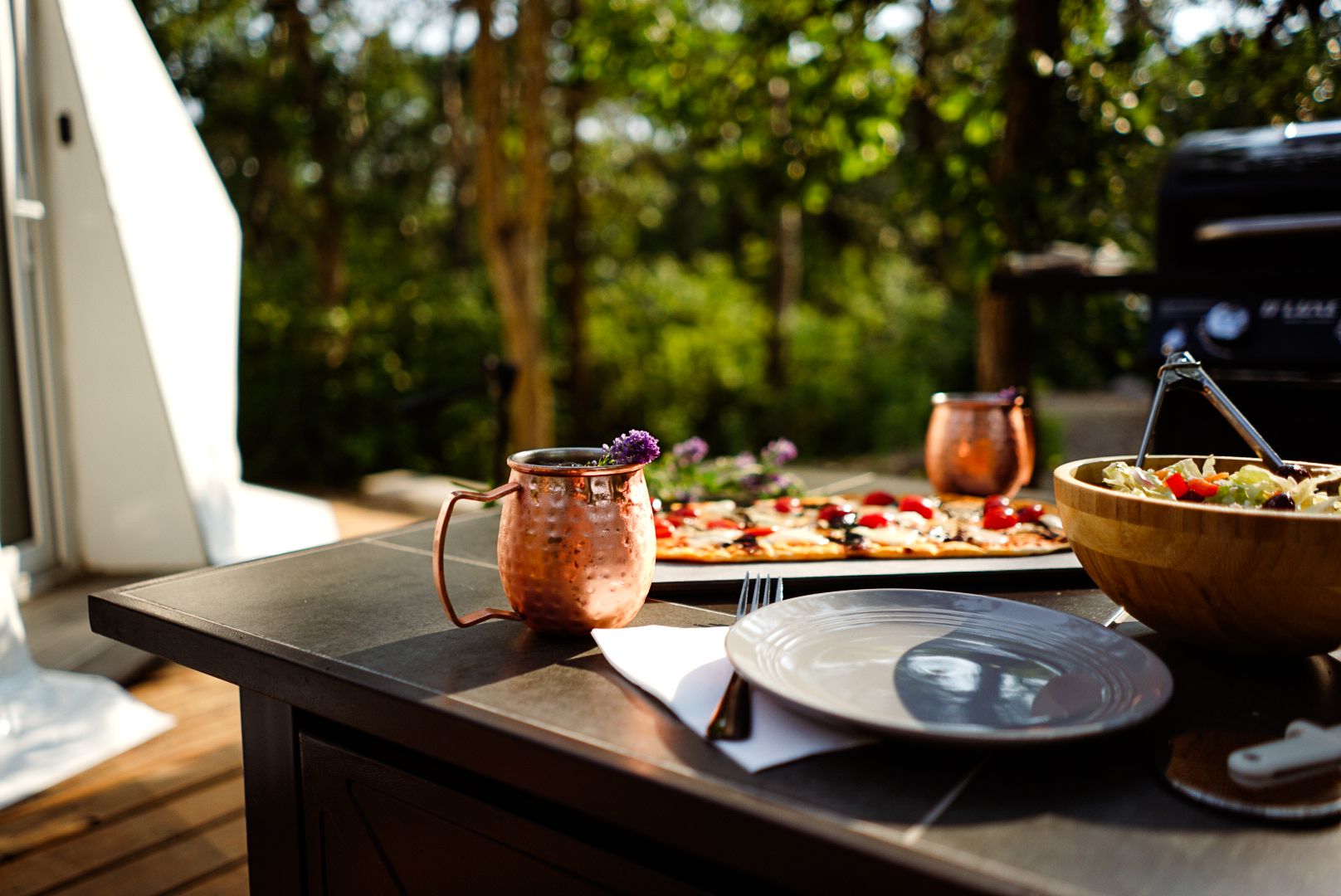 Wooden table set with drinks and appetizers inside a luxury glamping dome.