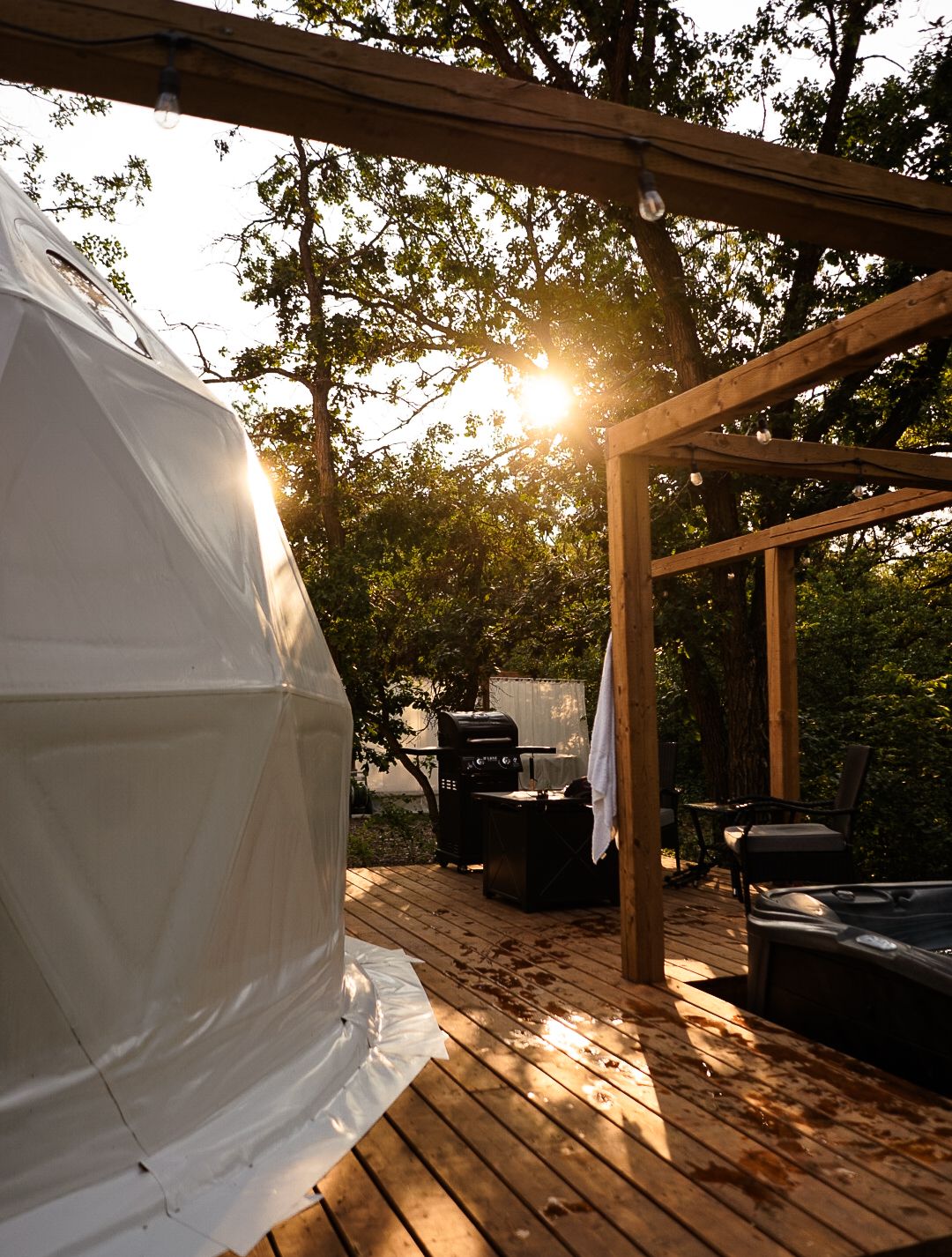 Wooden deck with outdoor furniture and white dome structure catching golden sunset light.