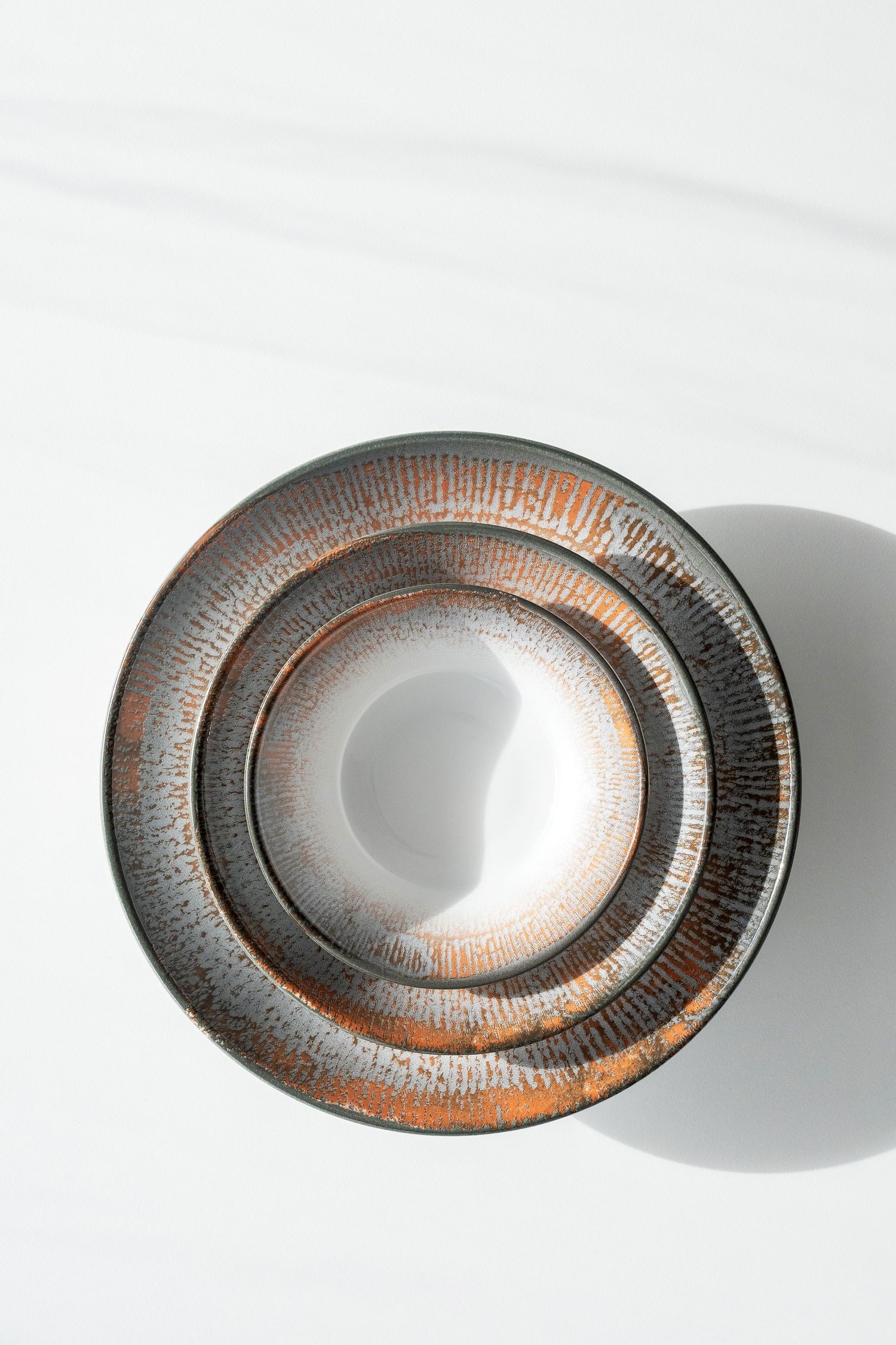 Shell collection: Porcelain plates and bowls with digitally printed radial patterns in shades of blue, brown, and grey.