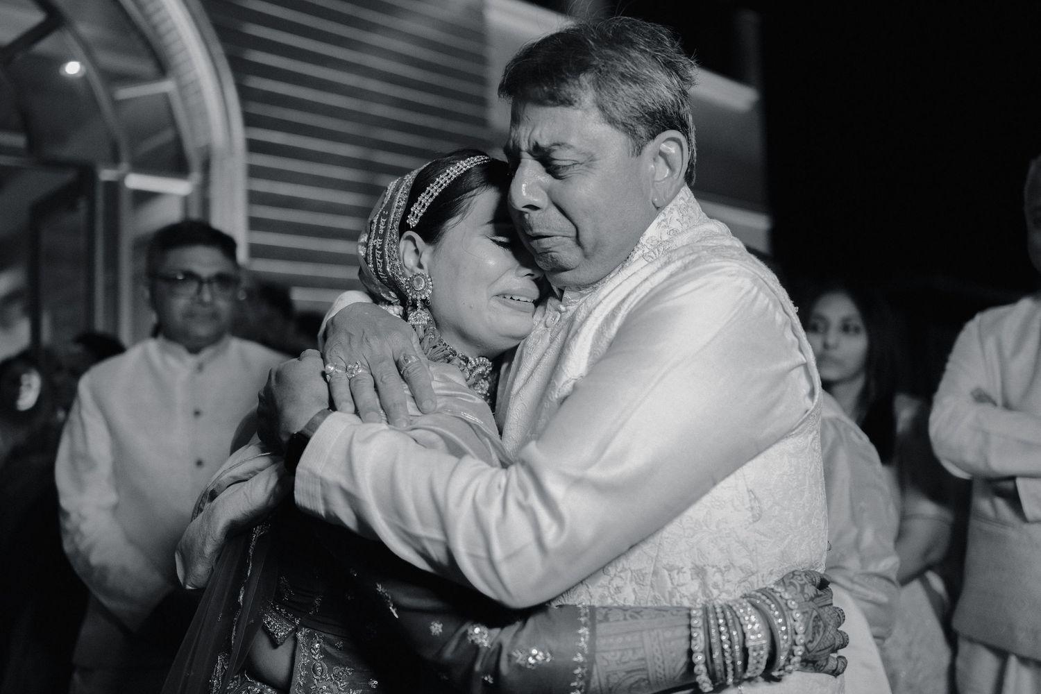 Emotional black and white photo capturing tender embrace during an Indian wedding ceremony.