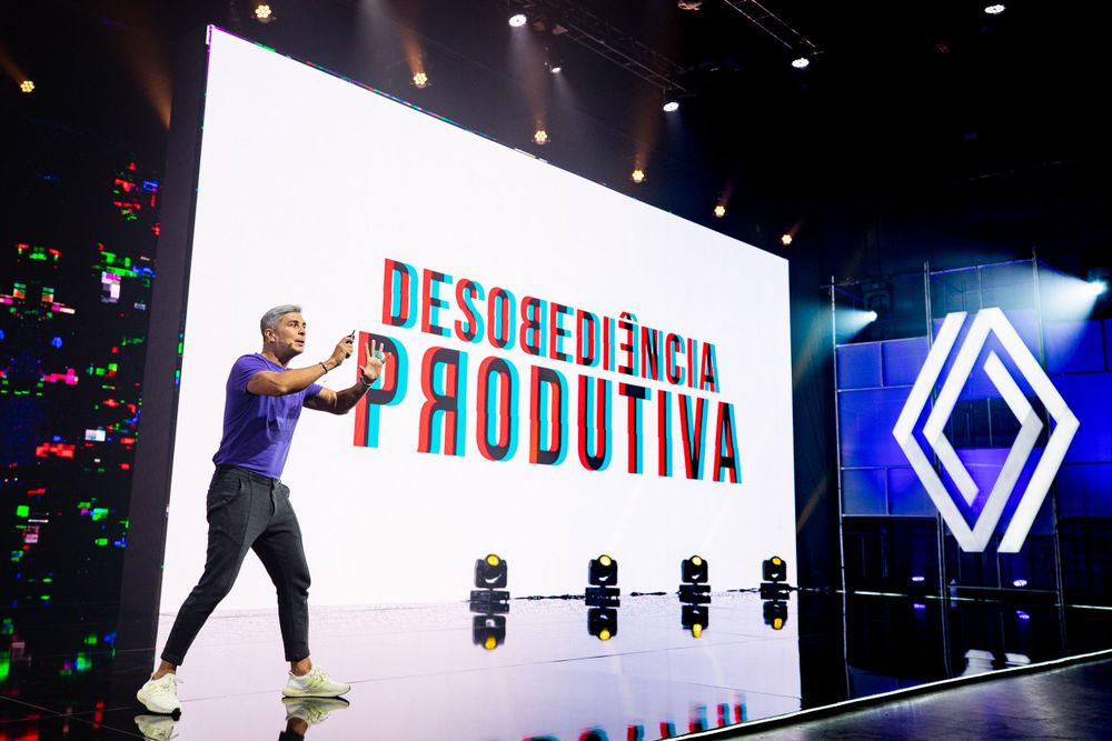 Large LED display screen showing text at automotive event with blue lighting effects.