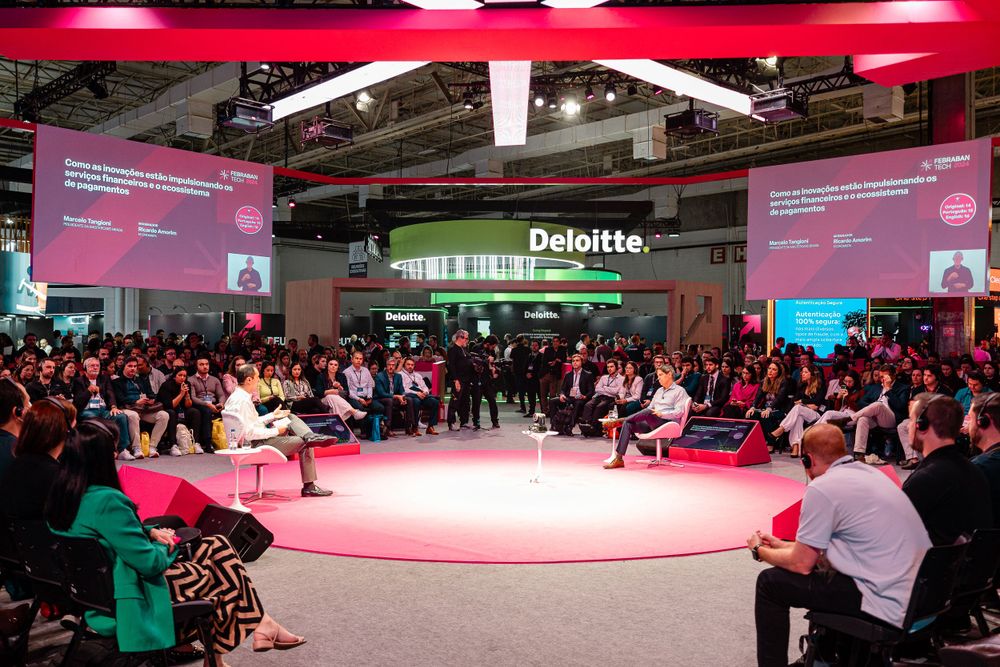 Corporate event space with red and pink lighting design and audience seating.