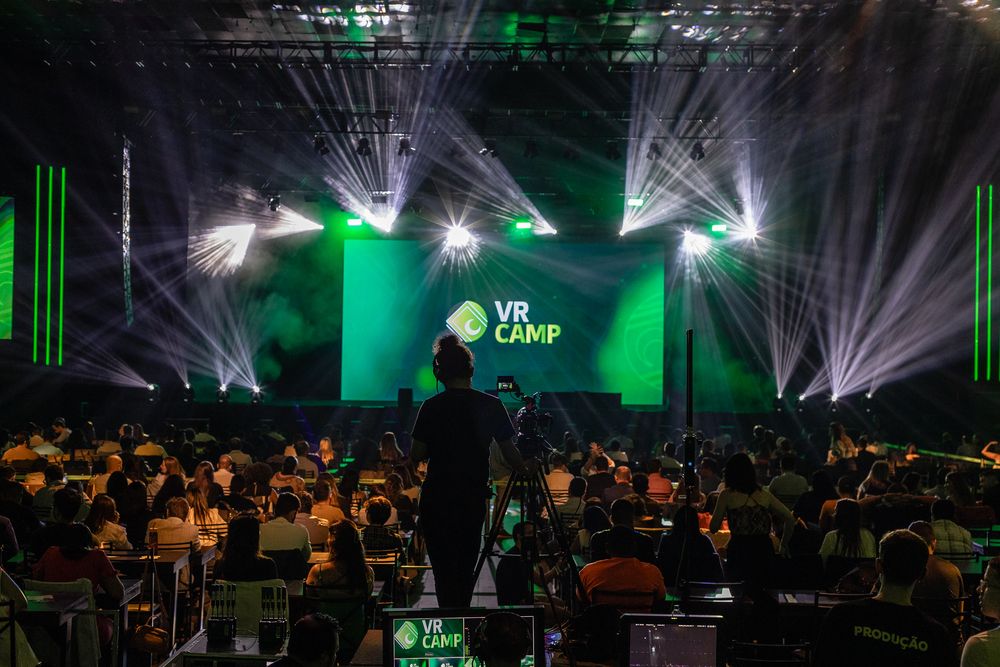 Conference venue with dramatic green lighting and multiple projection screens.