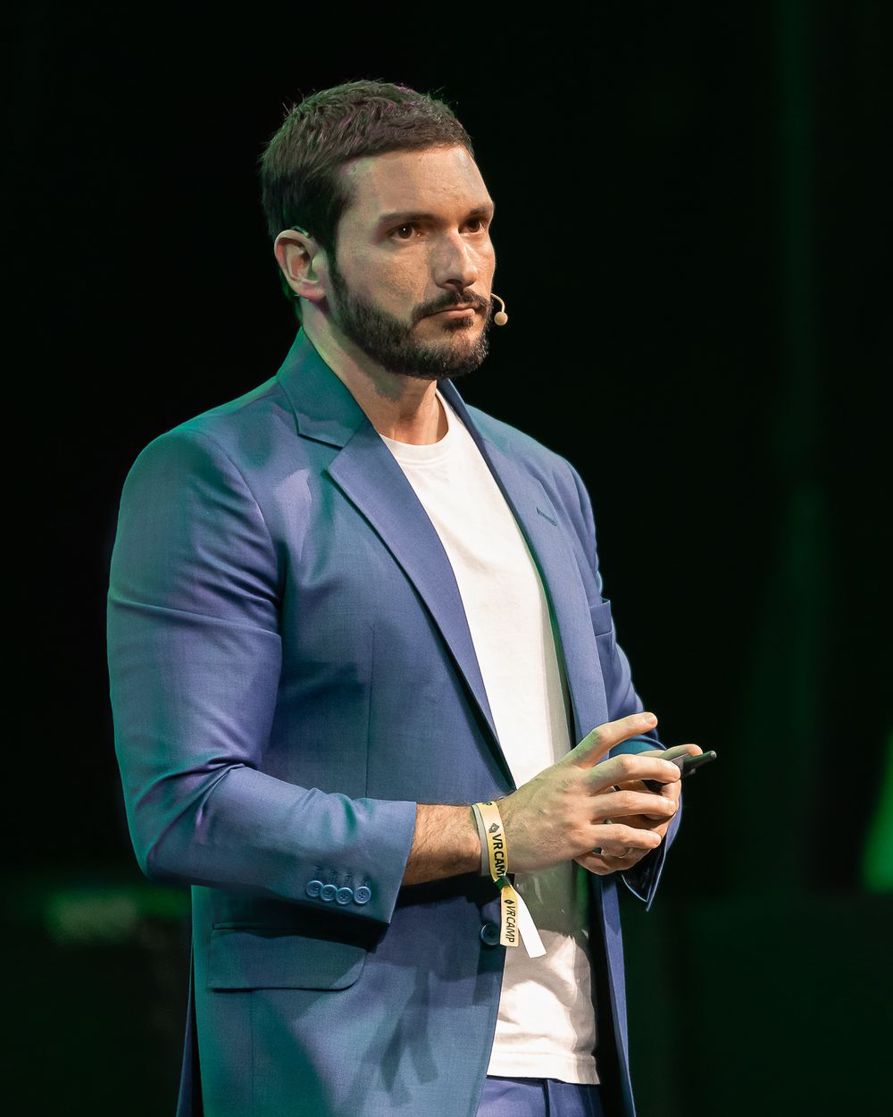Speaker in blue blazer and white shirt presenting on stage with animated gestures.