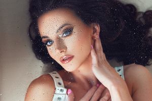 Glamour portrait with sparkling makeup and jeweled details in dark lighting.