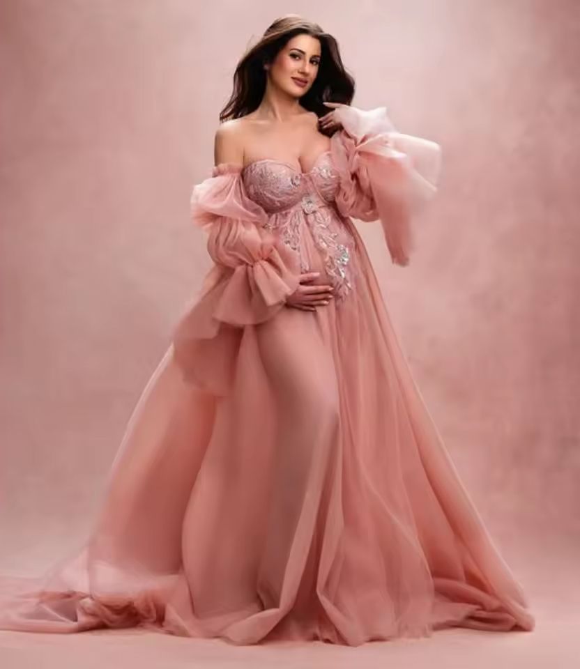 A dreamy maternity photoshoot in a flowing dusty rose gown with soft lighting and ethereal atmosphere.