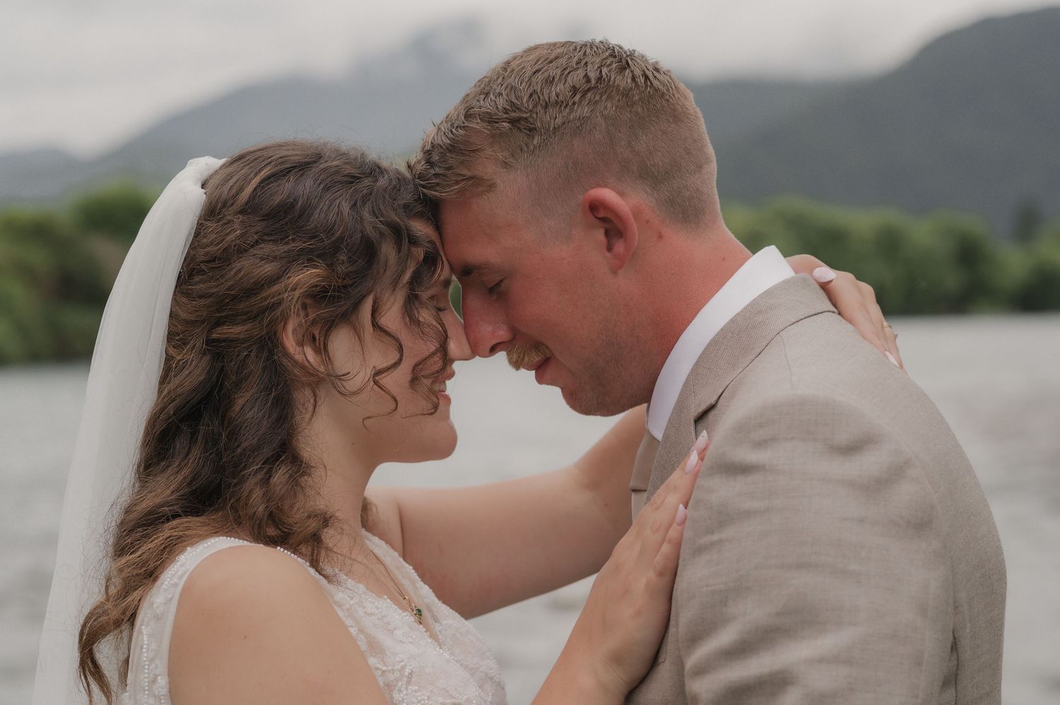 A romantic wedding couple sharing a candid moment at sunset against an urban backdrop.
