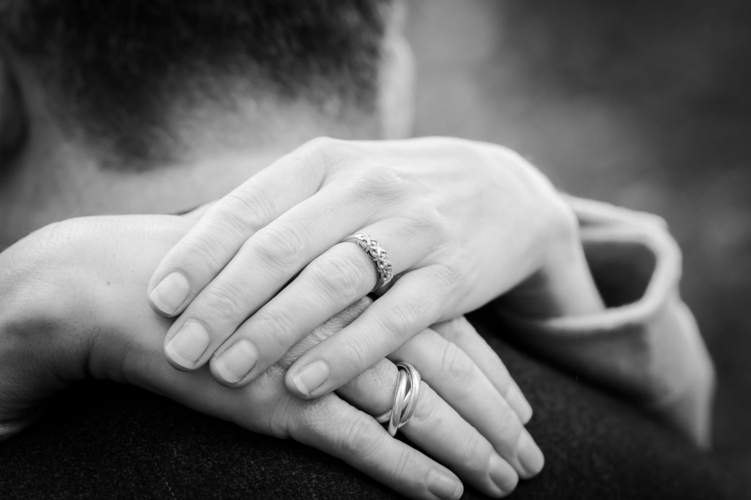 Close-up shot of hands displaying engagement rings during a photoshoot.