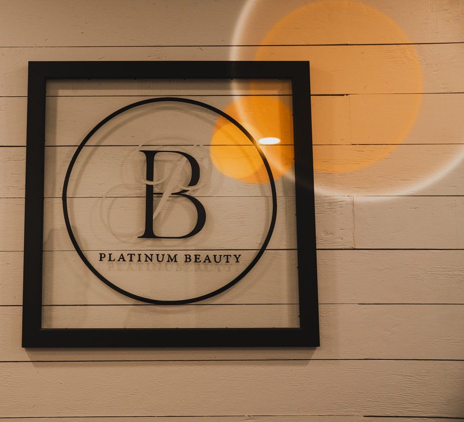 Black framed Platinum Beauty logo mounted on white wooden wall with ambient lighting.