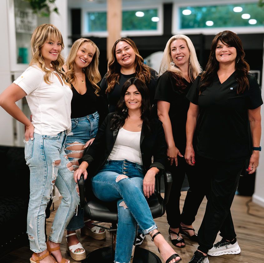 Group of salon professionals posing together in a modern beauty studio setting.