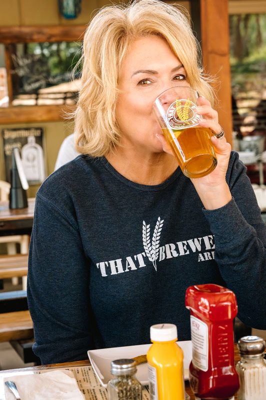 Person in black THAT brewery sweatshirt enjoying a beer at outdoor restaurant.