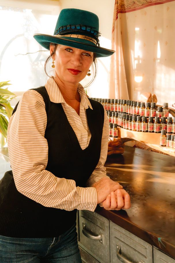 Person wearing green hat and striped shirt standing by display of essential oil bottles.