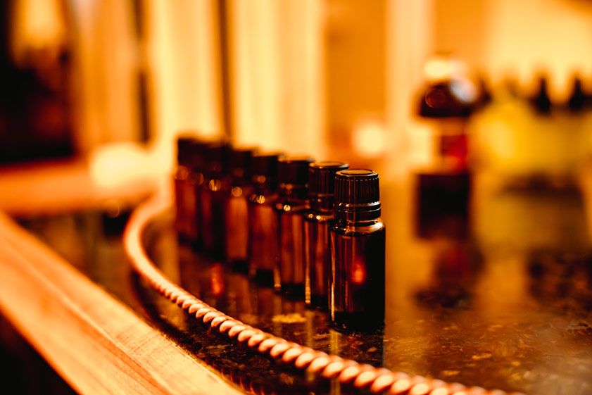 Close-up of amber glass bottles arranged in curved line on dark surface.