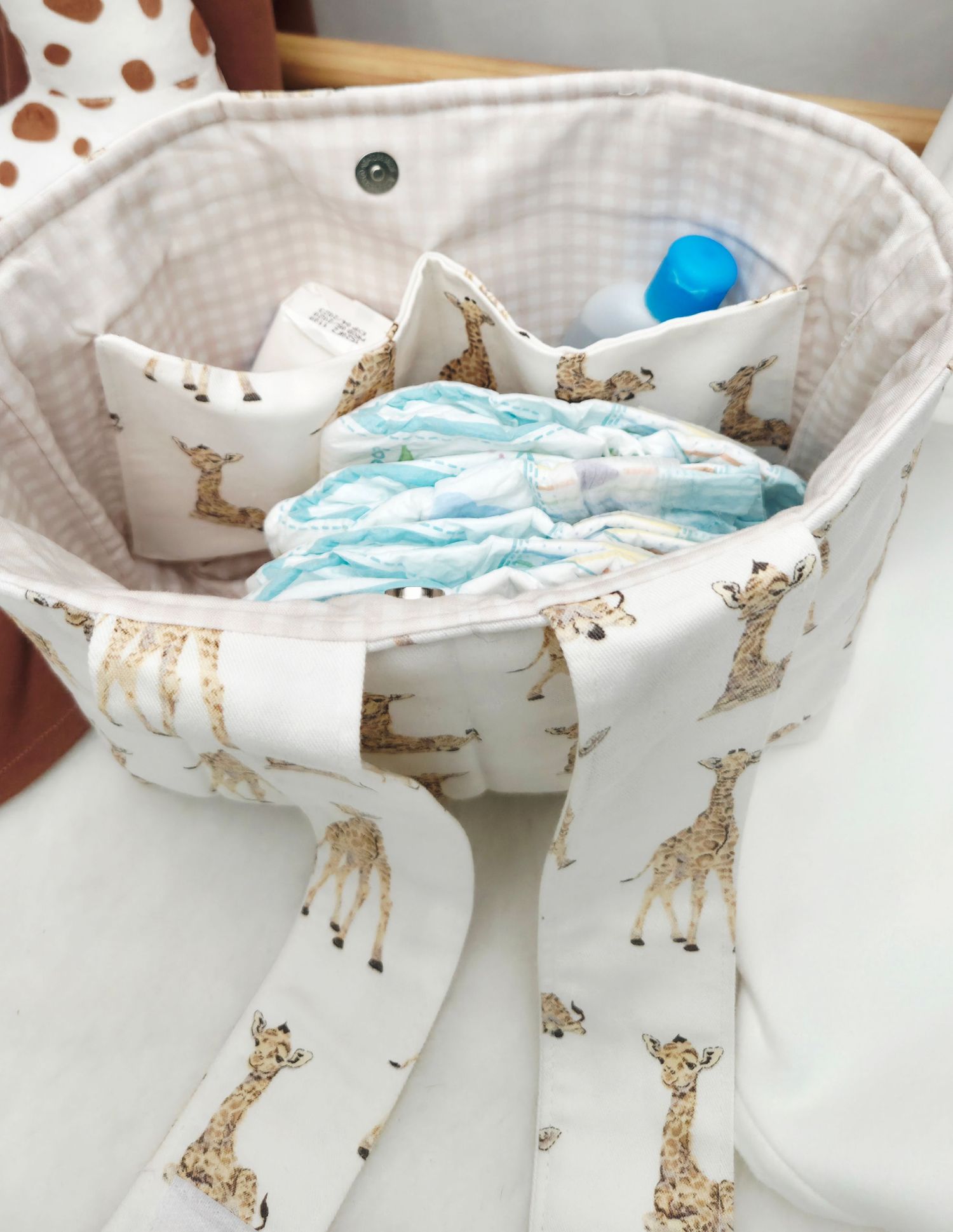 Giraffe print fabric diaper bag organizer filled with diapers and baby supplies, featuring a cute safari animal pattern.