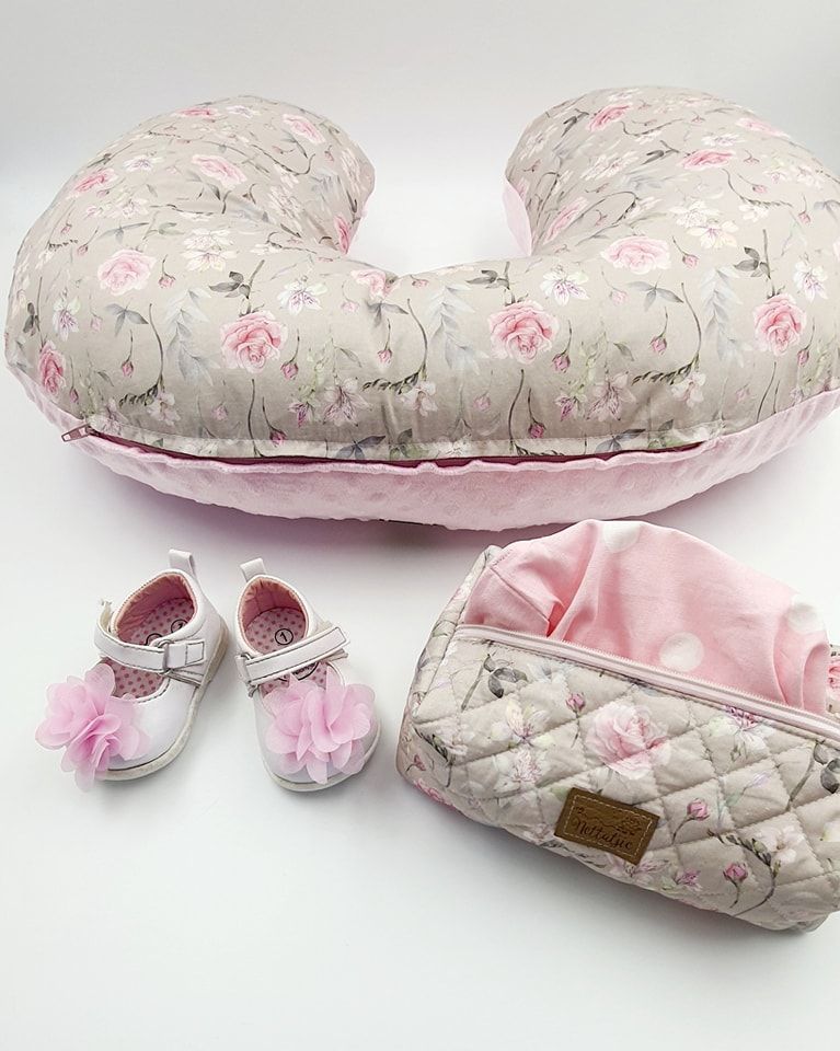 Floral print nursing pillow with matching baby shoes and accessories on white background.