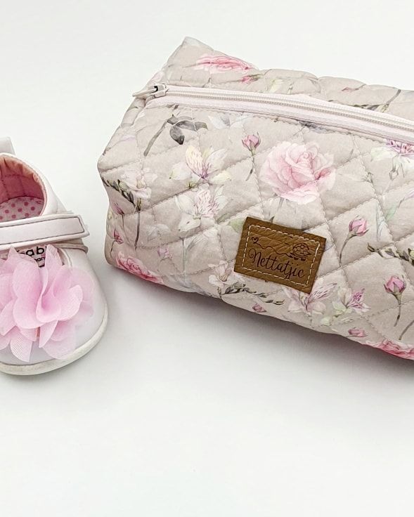 Floral patterned nursing pillow cover with delicate pink roses and gray branches on cream background.