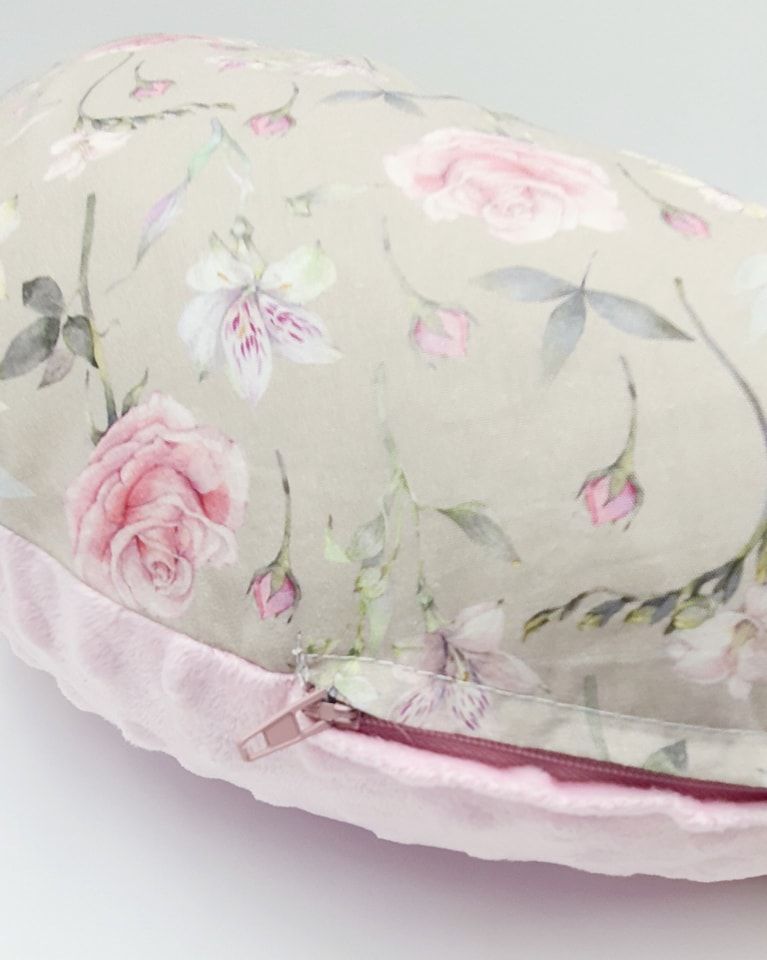 Elegant floral nursing pillow with soft pink roses and delicate gray leaves on light background.