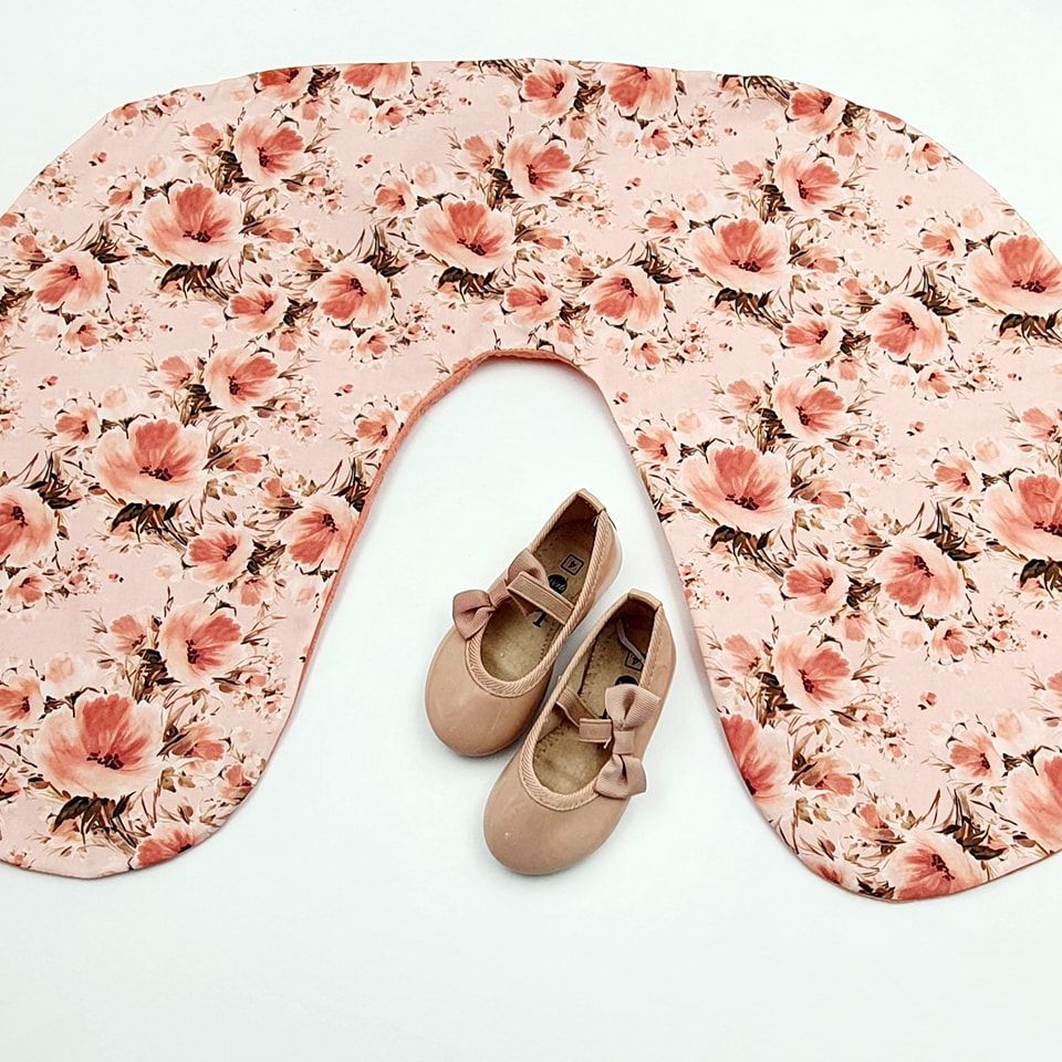 Pink floral nursing pillow cover with rose gold baby shoes.