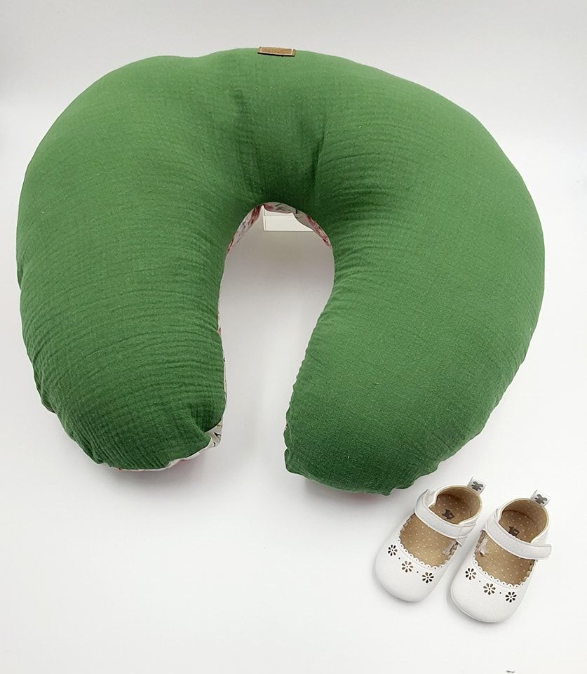 Green muslin nursing pillow with brown and white infant shoes.