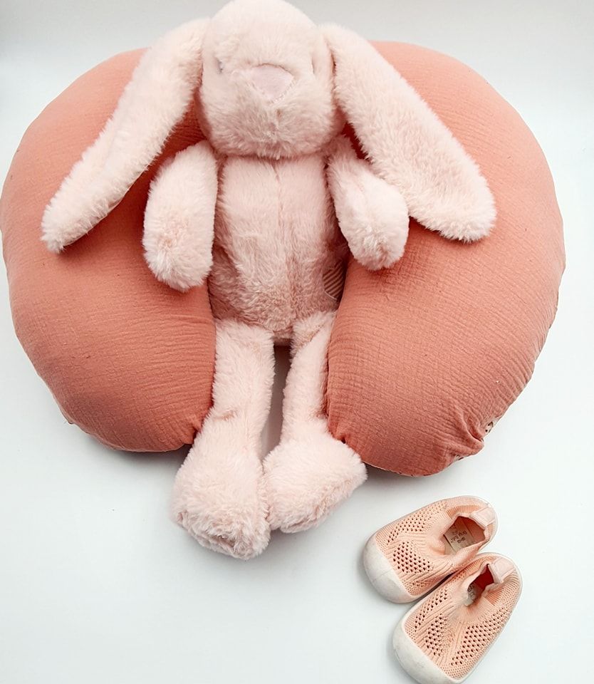 Coral nursing pillow with pink plush bunny and matching shoes.