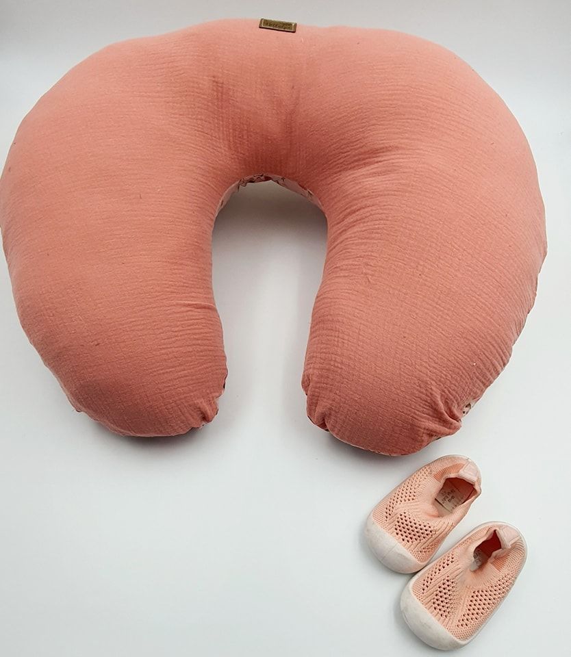 Solid coral-colored nursing pillow with attached baby shoes displayed in multiple views.