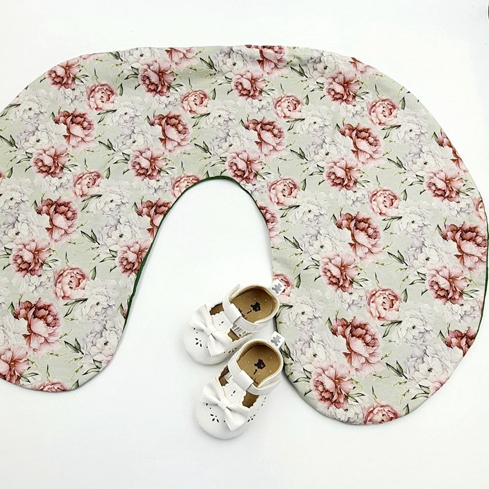 White and pink floral print nursing pillow cover with decorative pattern shown flat.