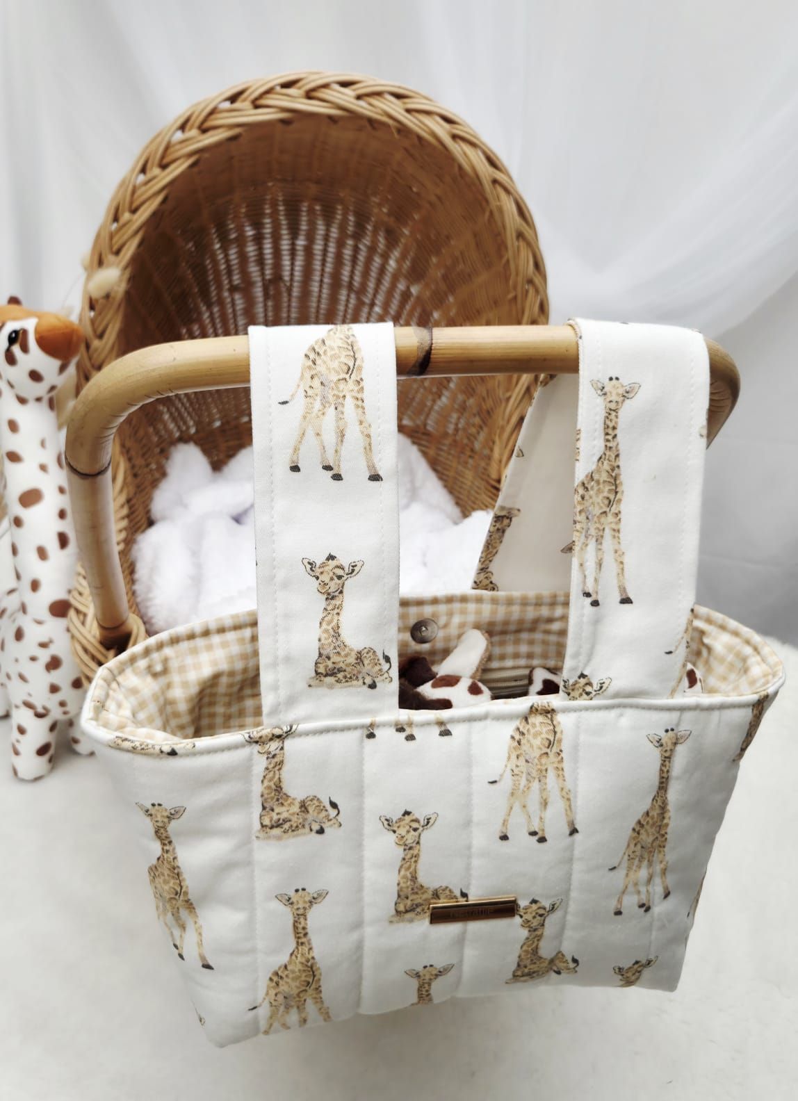 Giraffe print quilted tote bag with matching burp cloth set displayed in a wicker bassinet.